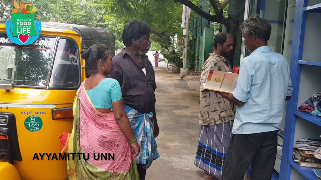 A community in Chennai gathering around a yellow tuk tuk.