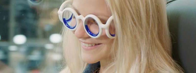 Woman on a train reading a book whilst wearing motion sickness glasses. (Source: Citroen)