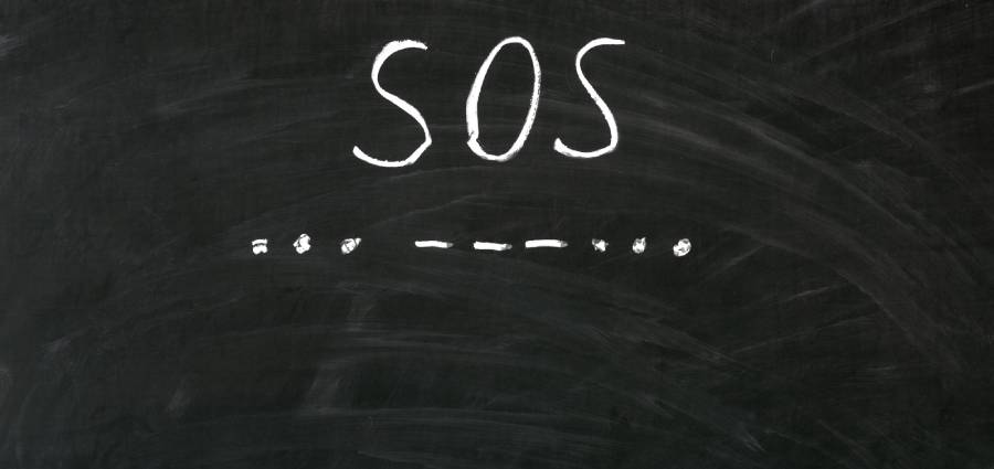 SOS word handwritten with white chalk on a blackboard (Photo: Shutterstock/Jurgis Mankauskas)