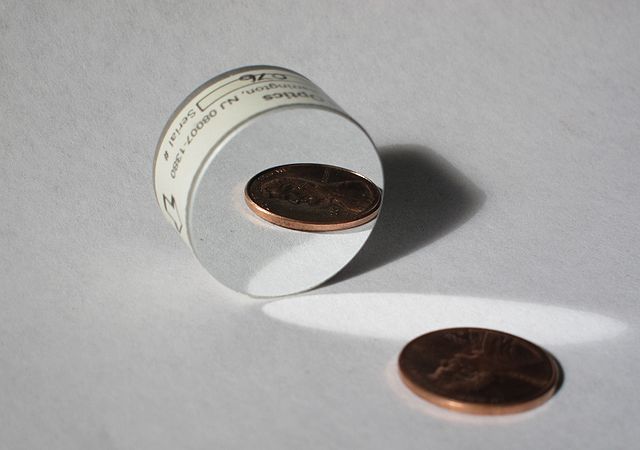 Photo of a first-surface mirror showing a coin being reflected (Photo: Wikimedia/Zaereth)