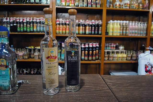 Mezcal bottles at a factory in Teotitlán del Valle, Oaxaca. The more expensive the bottle of Mezcal the less likely it is to contain a worm. (Photo: Wikimedia/ProtoplasmaKid)