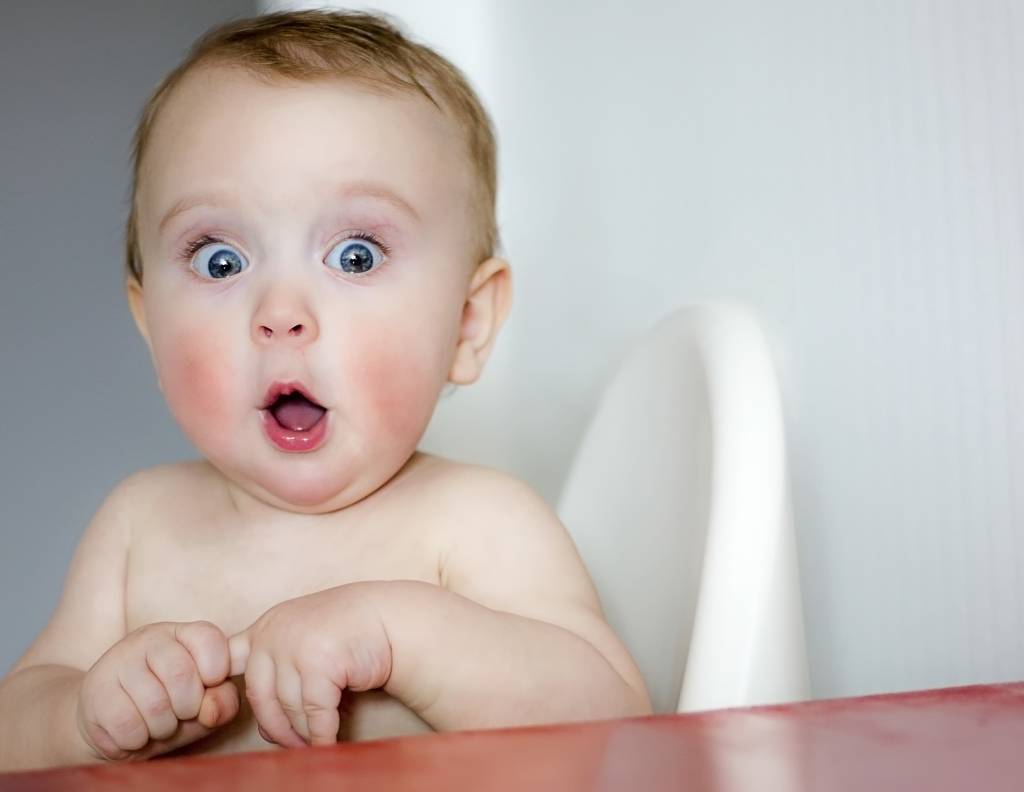 Surprised kid sitting at table. Child's eyes widened and mouth opened in amazement. (Photo: Shutterstock/EvgeniiAnd)
