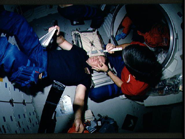 STS-41 crewmembers conduct Detailed Supplementary Objective (DSO) 472, Intraocular Pressure on the middeck of Discovery, Orbiter Vehicle (OV) 103. Mission Specialist (MS) William M. Shepherd rests his head on the stowed treadmill while Pilot Robert D. Cabana, holding Shepherd's eye open, prepares to measure Shepherd's intraocular pressure using a tonometer (in his right hand). (Photo: Wikimedia/NASA)