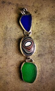 Three Fordite pendants resembling a Shakespearean Fairy Tale, displayed on a table.