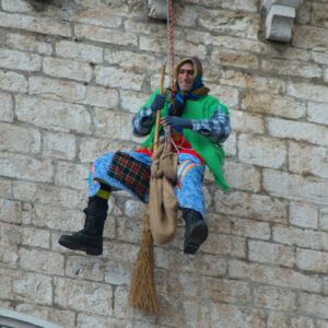An Italian firefighter in the role of the Befana descends from the Palazzo dei Consoli in Gubbio, January 6, 2011. (Credit: Wikimedia)
