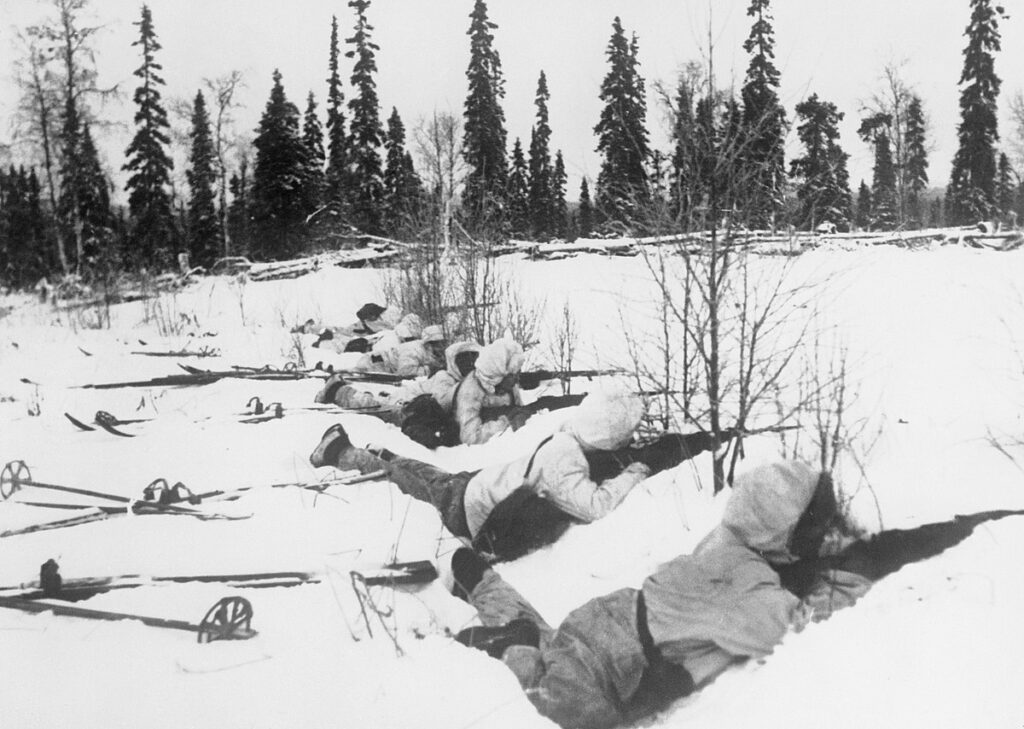 A Finnish ski patrol, lying in the snow on the outskirts of a wood in Northern Finland, on the alert for Russian troops, 12 January 1940.
