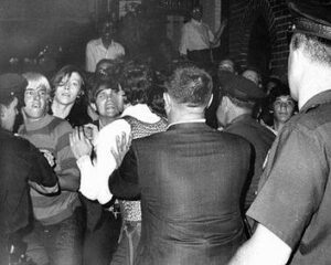 Rioting gay youth confront police in Joseph Ambrosini's historic photograph captured on the first night of the Stonewall riots. The image depicts the escalation of tensions as police force people back outside the Stonewall Inn on June 28, 1969.