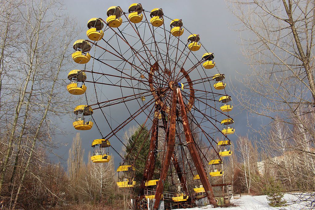 The eerily silent Ferris wheel, its structure succumbing to rust, stands as a haunting symbol of past joy in Pripyat's Amusement Park, nestled within the confines of the Chernobyl Exclusion Zone.